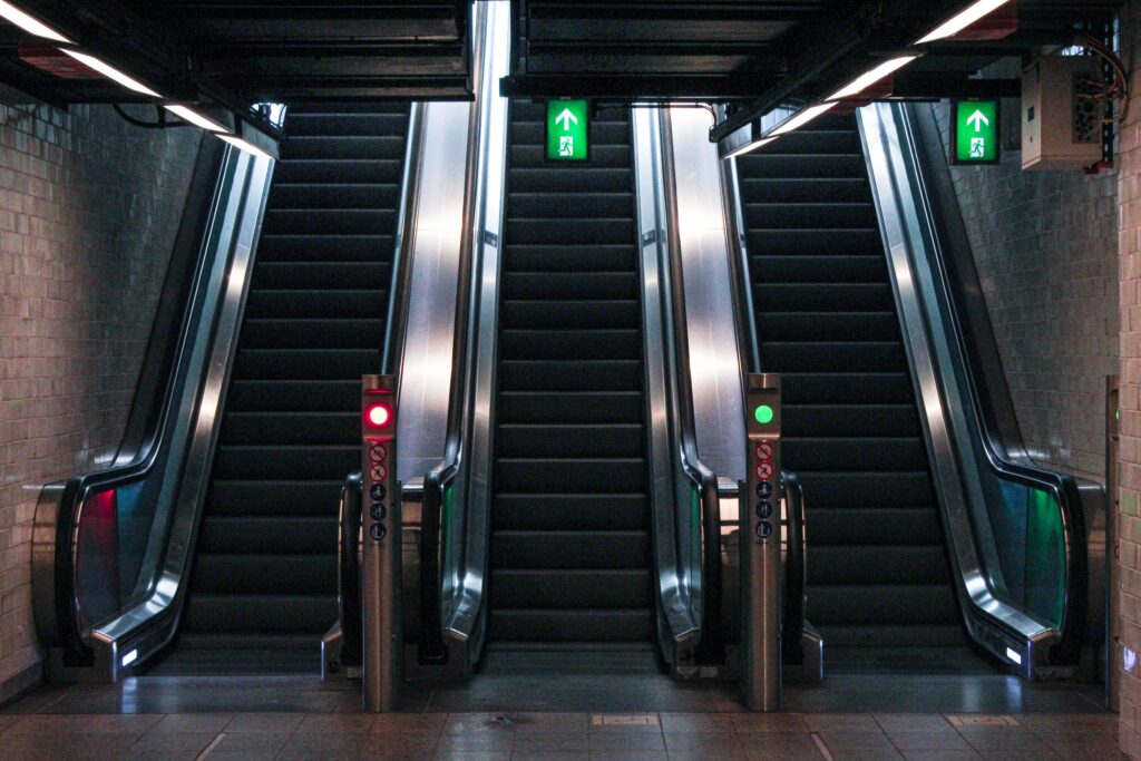 Three escalators viewed from the bottom up with red and green lights between them